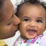 African American Mother kissing young infant fshutterstock_72019543